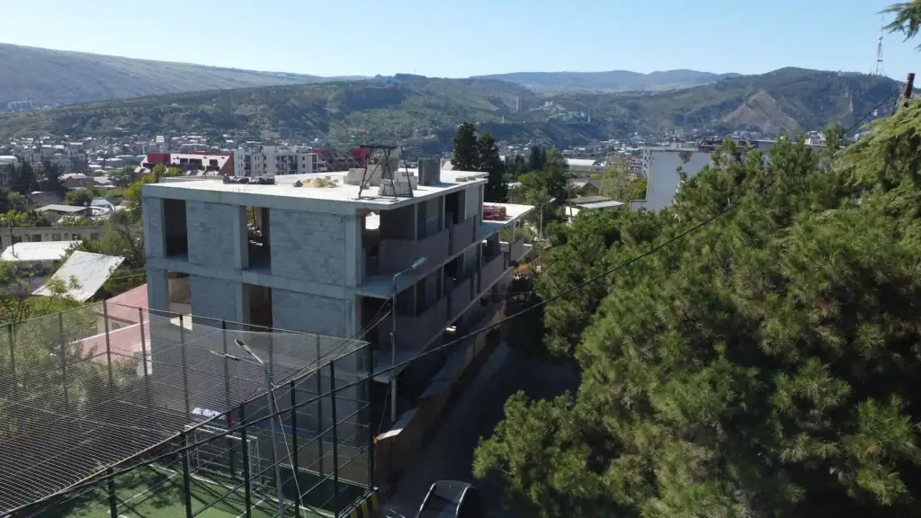 Tbilisi Real Estate – realestate development Real estate investment building in Tbilisi: Drone view of Avlabari real estate Real estate investment projects in Tbilisi - Avlabari office building under construction / LD Estates mid-rise building with city and mountain backdrop