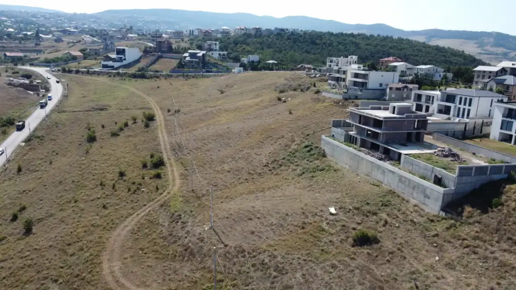 Tbilisi real estate investment opportunity: Drone view of non-agricultural construction-ready development land at Tabor Hill with nearby villas and road access – LD Estates