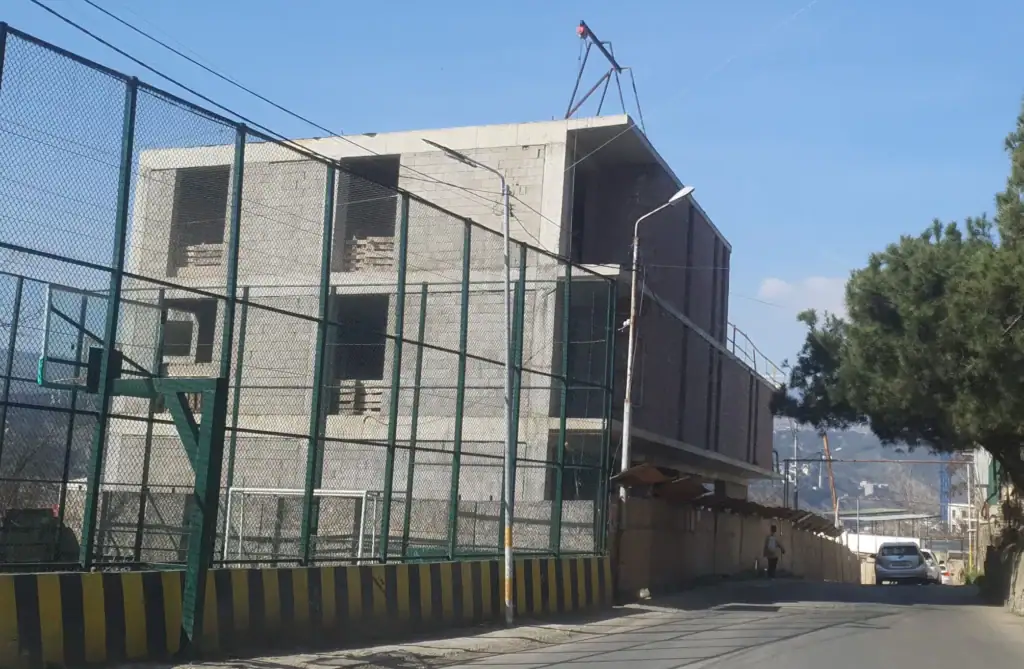 Real estate investment projects in Tbilisi: View of multi-story investment building under construction in Avlabari, Tbilisi with adjacent sports court and scaffolding