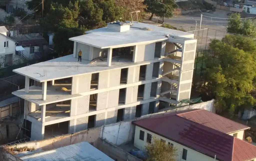 Real estate investment projects in Tbilisi: Close-up of multi-level investment building under construction in Avlabari, Tbilisi with rooftop view and structural framework