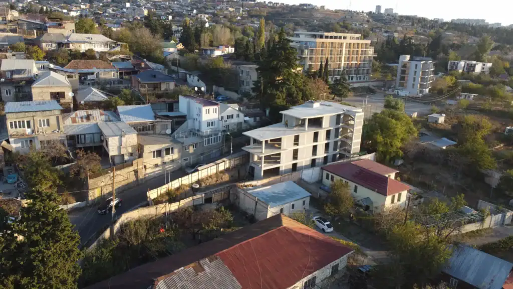 Real estate investment projects in Tbilisi: Aerial view of multi-story investment building under construction in Avlabari, Tbilisi, surrounded by residential houses and new developments