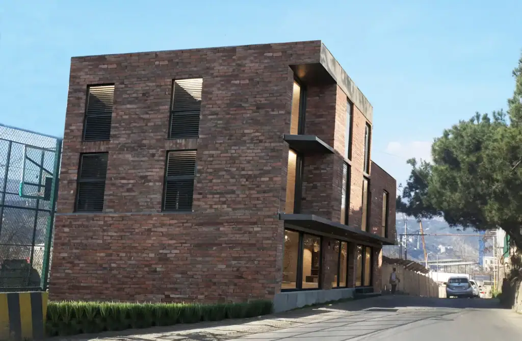 Tbilisi Real Estate Project Update – Avlabari Hill investment building with red brick facade, street view.