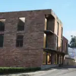 Tbilisi Real Estate Project Update – Avlabari Hill investment building with red brick facade, street view.