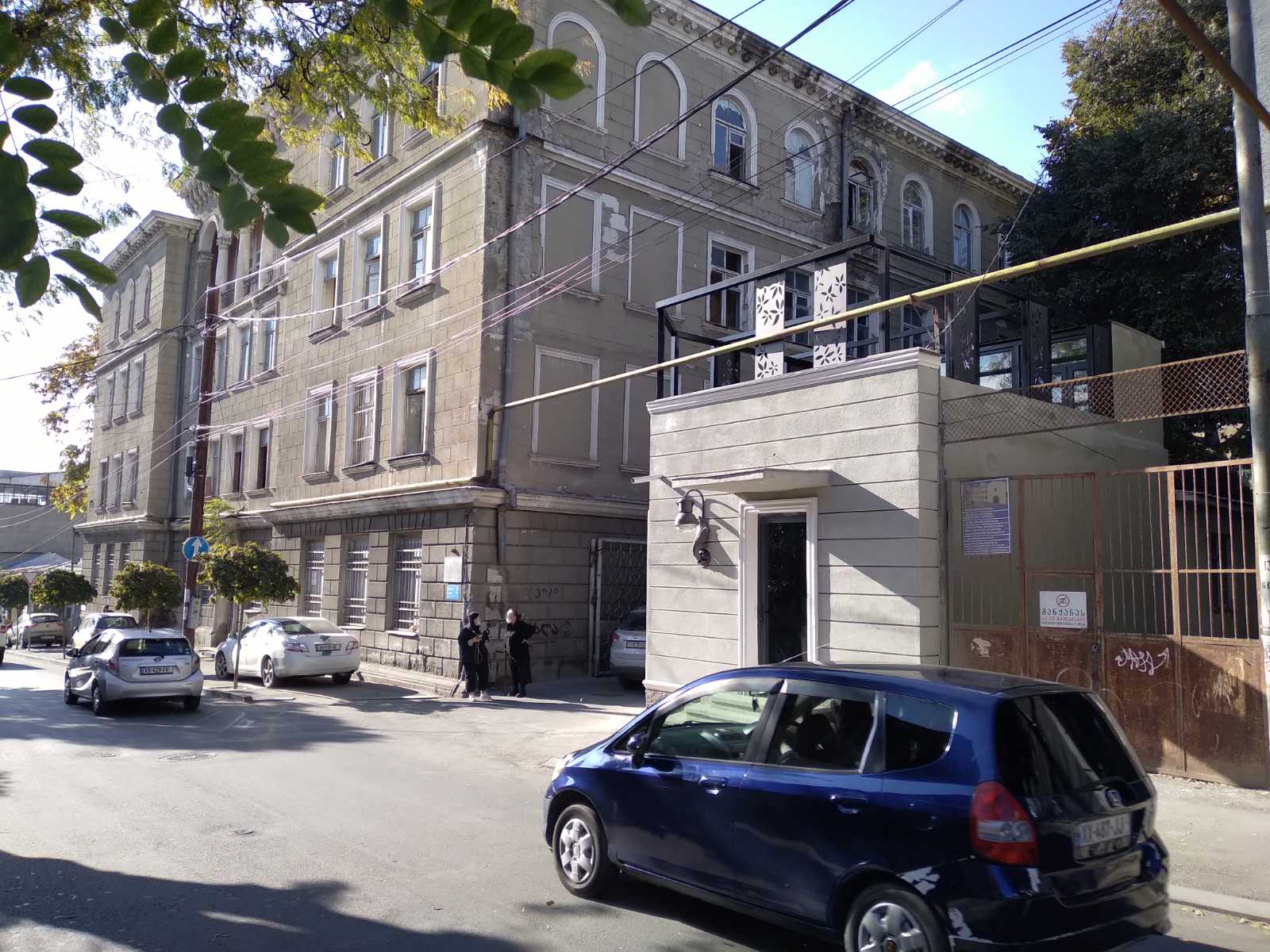Street-level view of the completed office building showing integration with historic Old Tbilisi neighborhood, adjacent heritage buildings visible