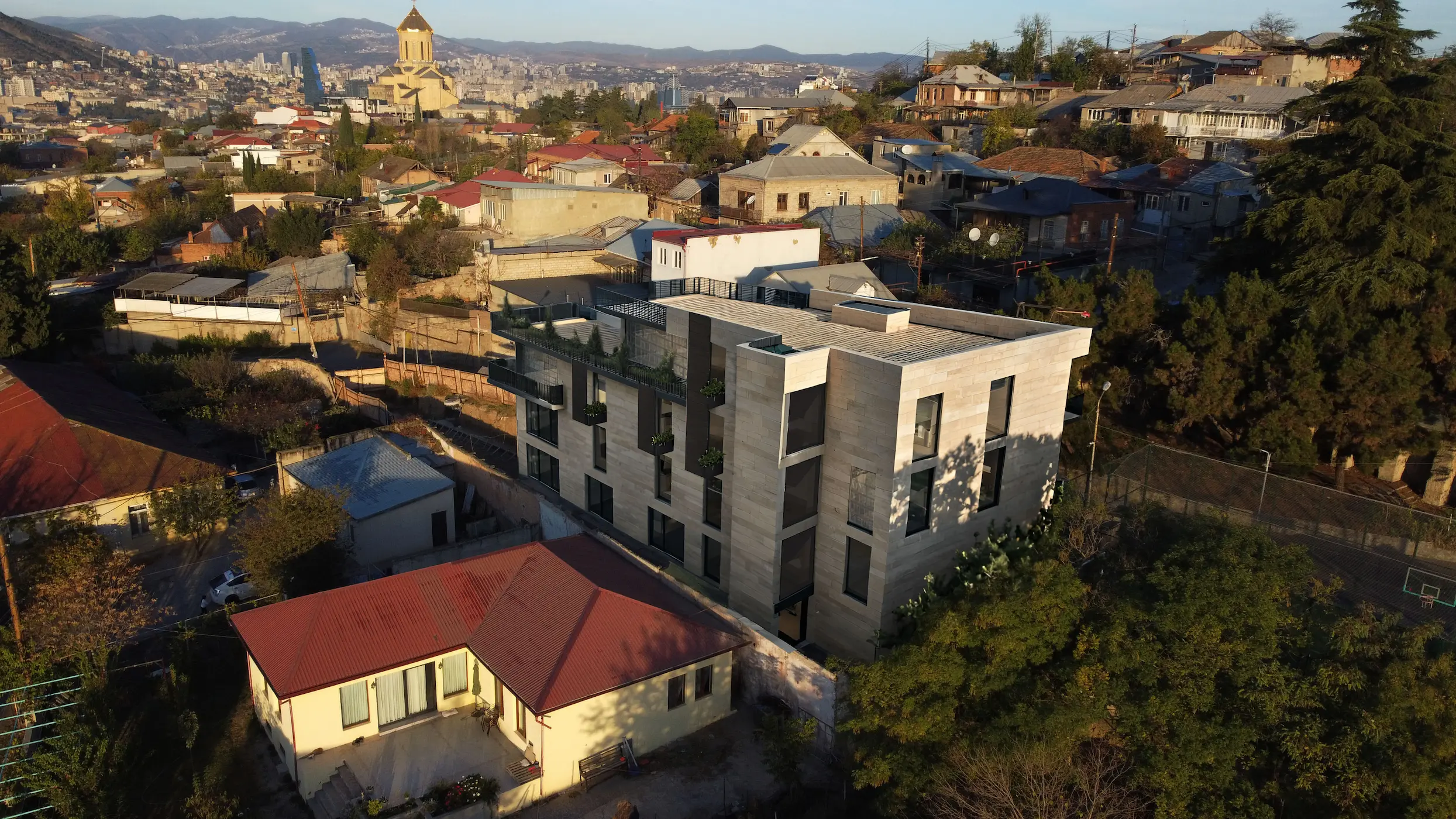 Architectural visualization of Avlabari building with stone-clad contemporary facade viewed from street angle — approved design concept, not current condition