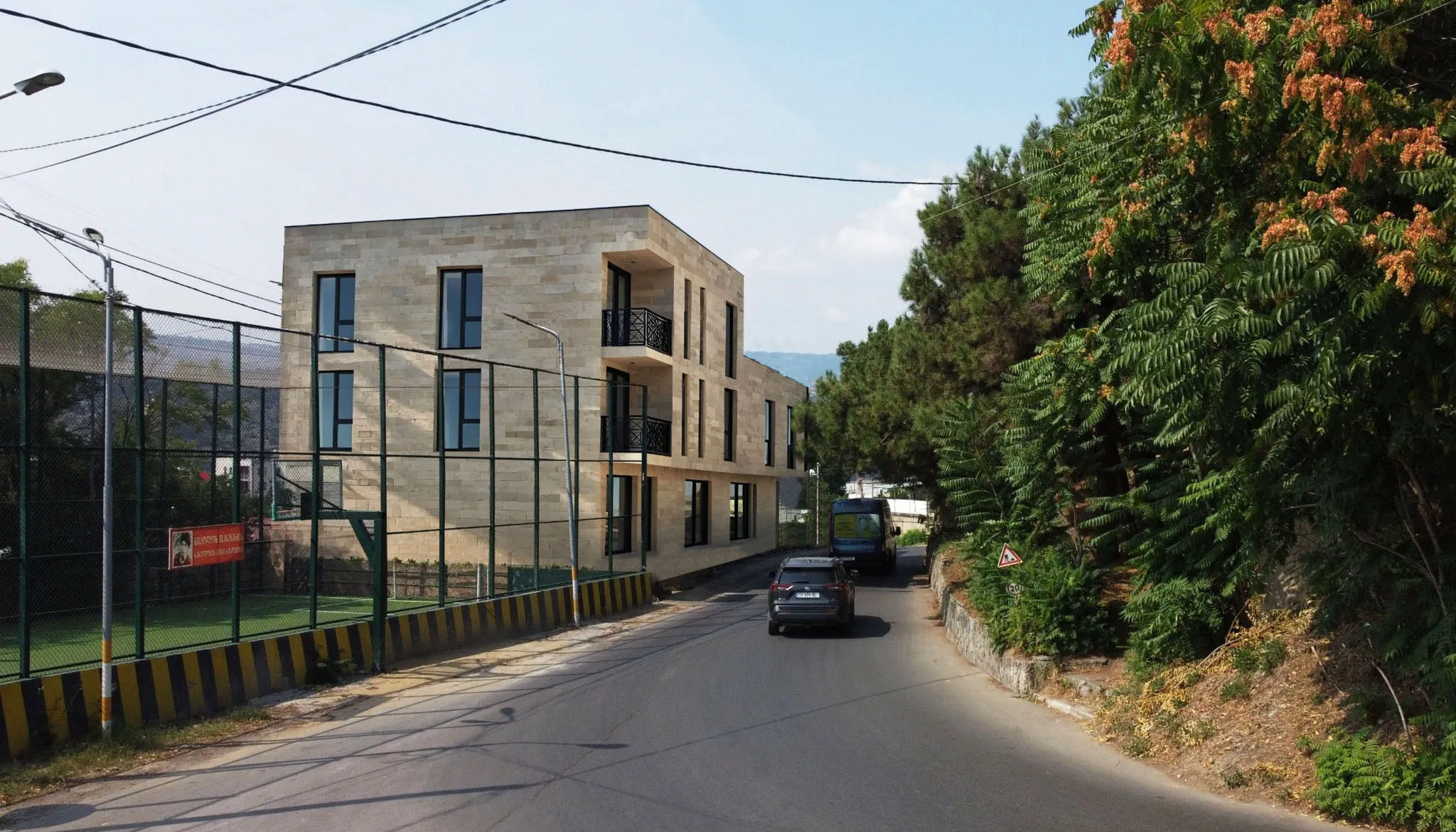 Architectural visualization showing completed four-story building with contemporary stone-clad facade, regular window pattern, corner balconies